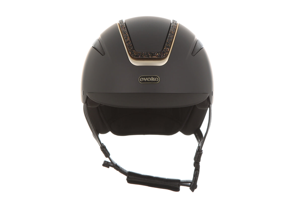A matte black riding helmet with a decorative gold and brown patterned trim on the top center, featuring the 'Evoke' brand logo on the front, set against a plain white background.